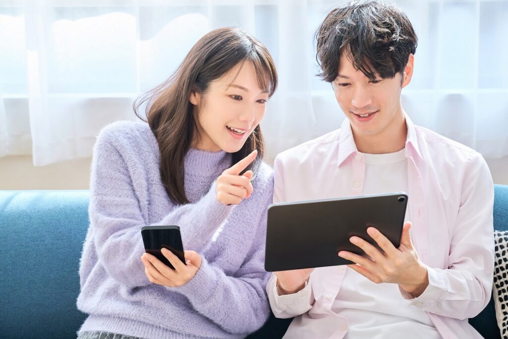 ソファーに座った男女が一緒にタブレットを見ている画像